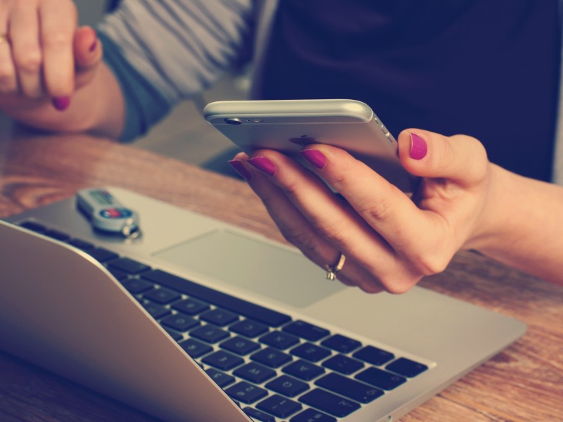 Person with a laptop holding a phone