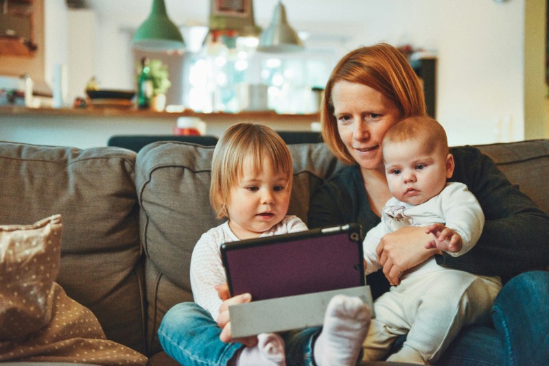 Family sitting on a couch looking at a tablet